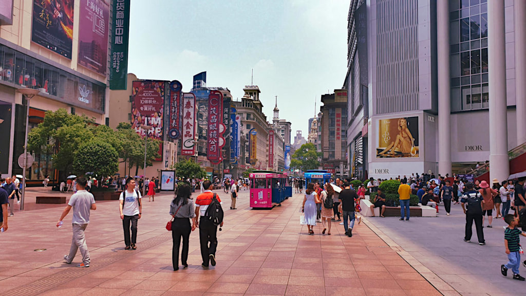 Nanjing Road busy with shoppers and decorated by many shop signs in English and Chinese