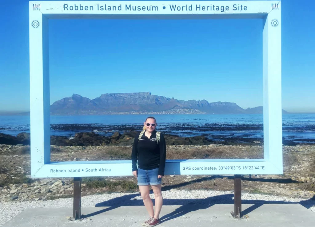 Zoe stood on Robben Island in front of a postcard-style picture spot that shows Table Mountain and Cape Town across the water.
