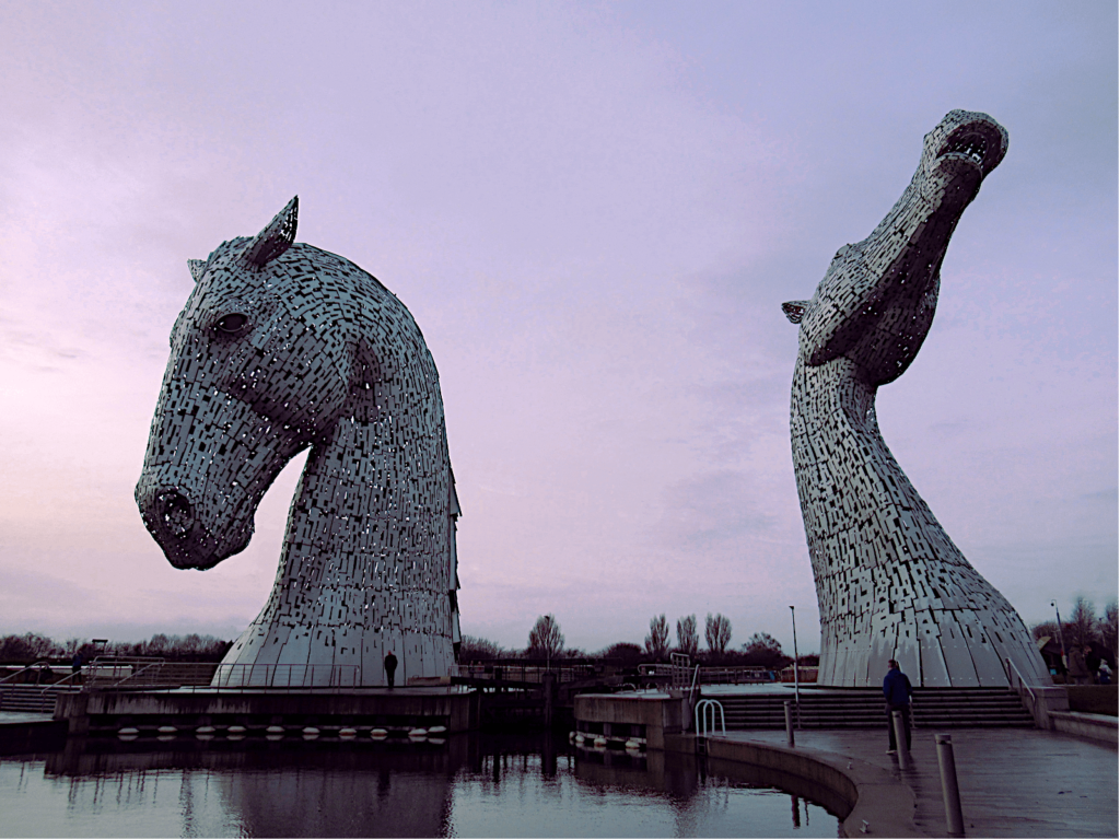 The two Kelpie heads in Falkirk are shown against a purple and pink dusk skyline.