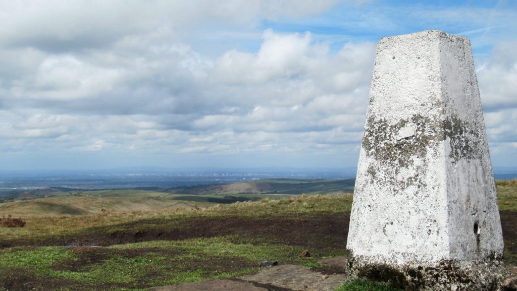 Looking north-west from the top of Shining Tor with Manchester in the background and the trig point in the foreground