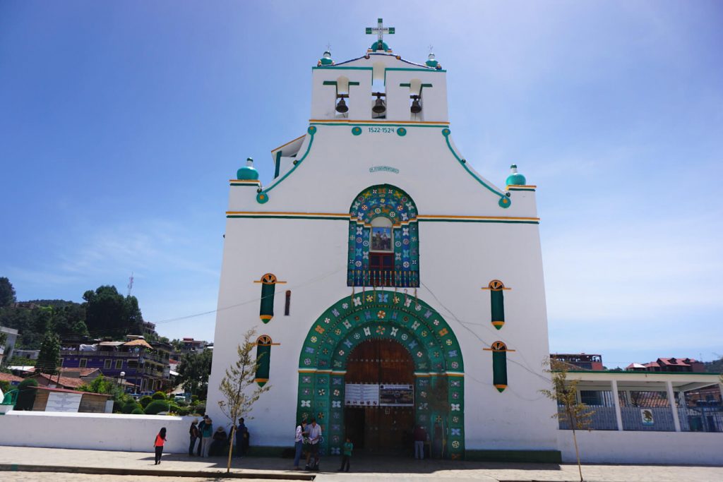 The church in San Juan Chamula. A white building with green surrounds on the doors and decoration. 