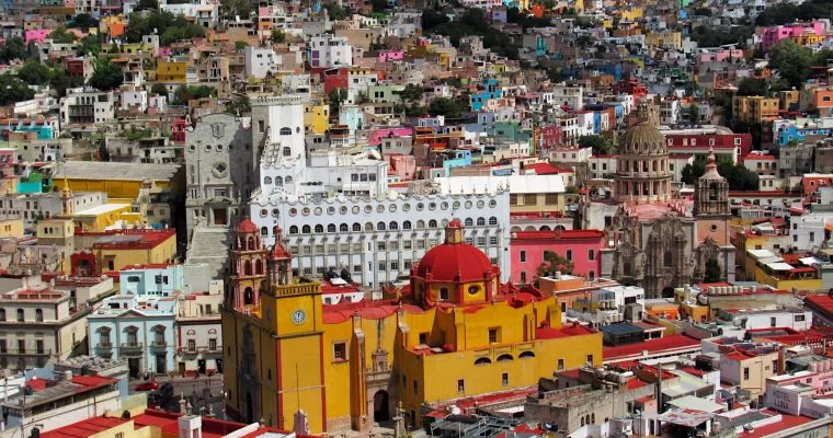 The bright buildings of Guanajuato in the background. Nearest the cameras are the iconic yellow Basilica and the University