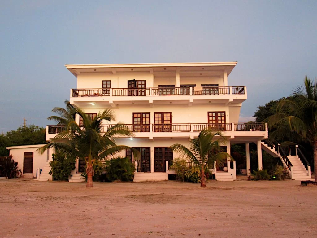 We'Yu hotel on the beach front. A white building, three floors and palm trees in front of it.