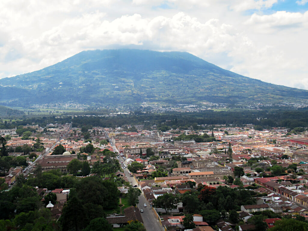 Volcan Agua overshadowing Antigua Guatemala. The top of the volcano is behind fluffy white clouds