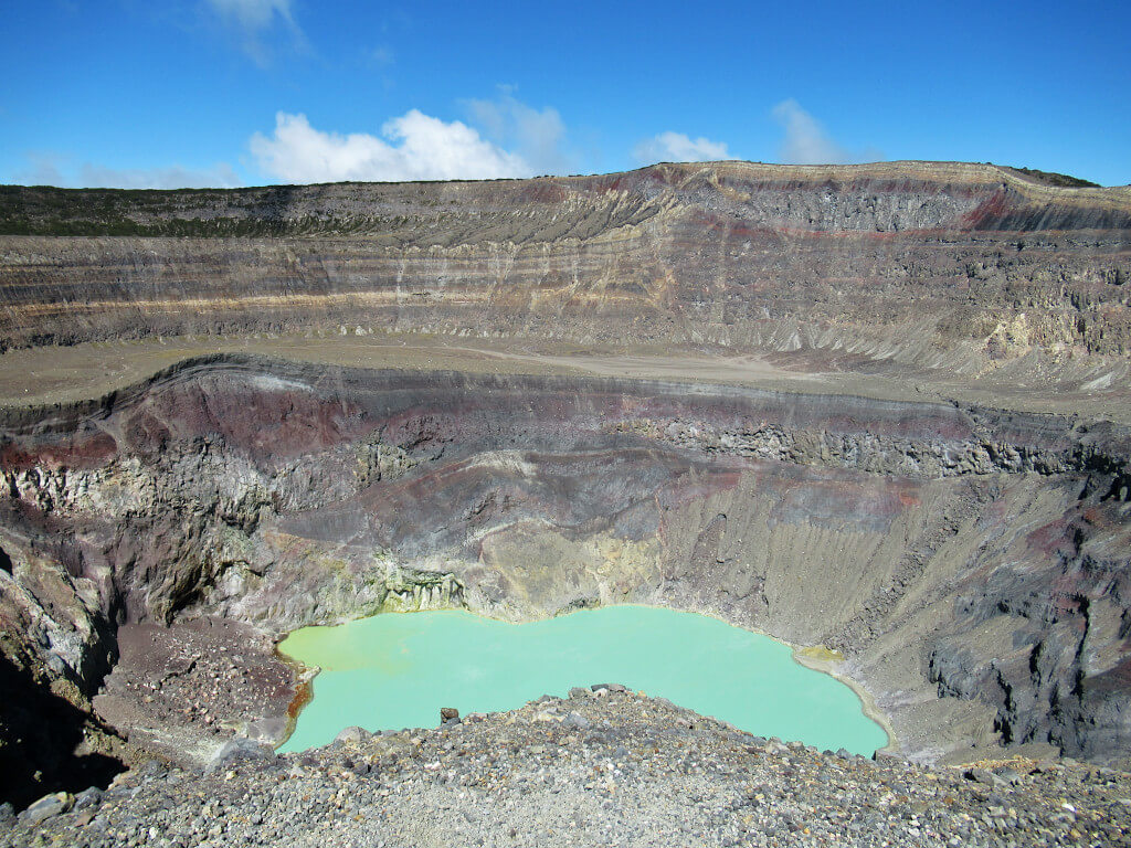 Inside the crater of Volcano Santa Ana with a bright green sulphur lake and layers of brightly coloured rocks