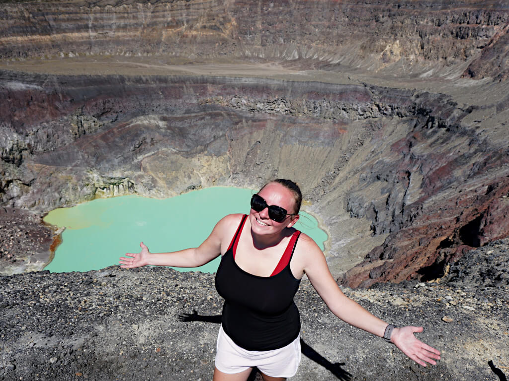 Zoe at the top of the volcano with the lake and crater behind her