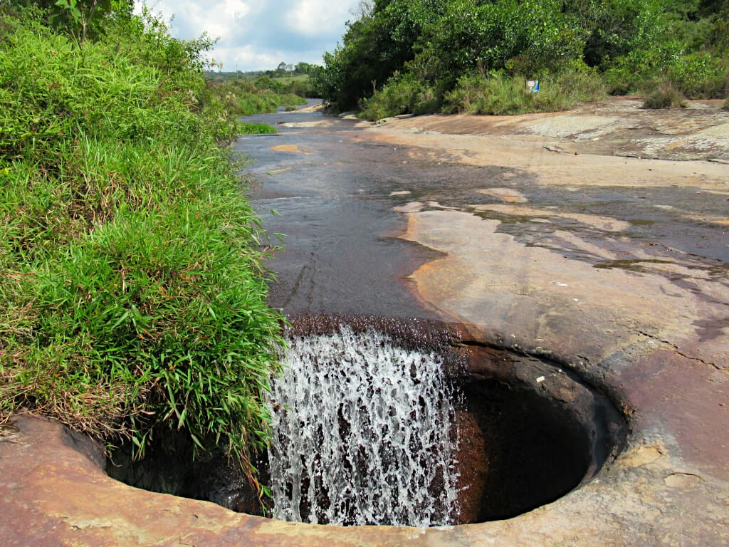 Water flows into a deep cave in the river bed