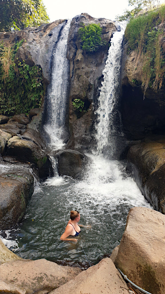 Zoe in the waterfall plunge pool holding onto the rope for safety!