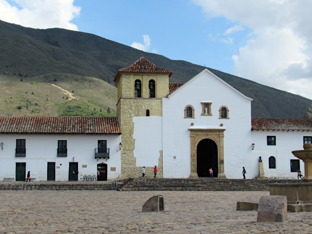 The main square in Villa de Leyva. The white church building is overshadowed by the large hills in the background