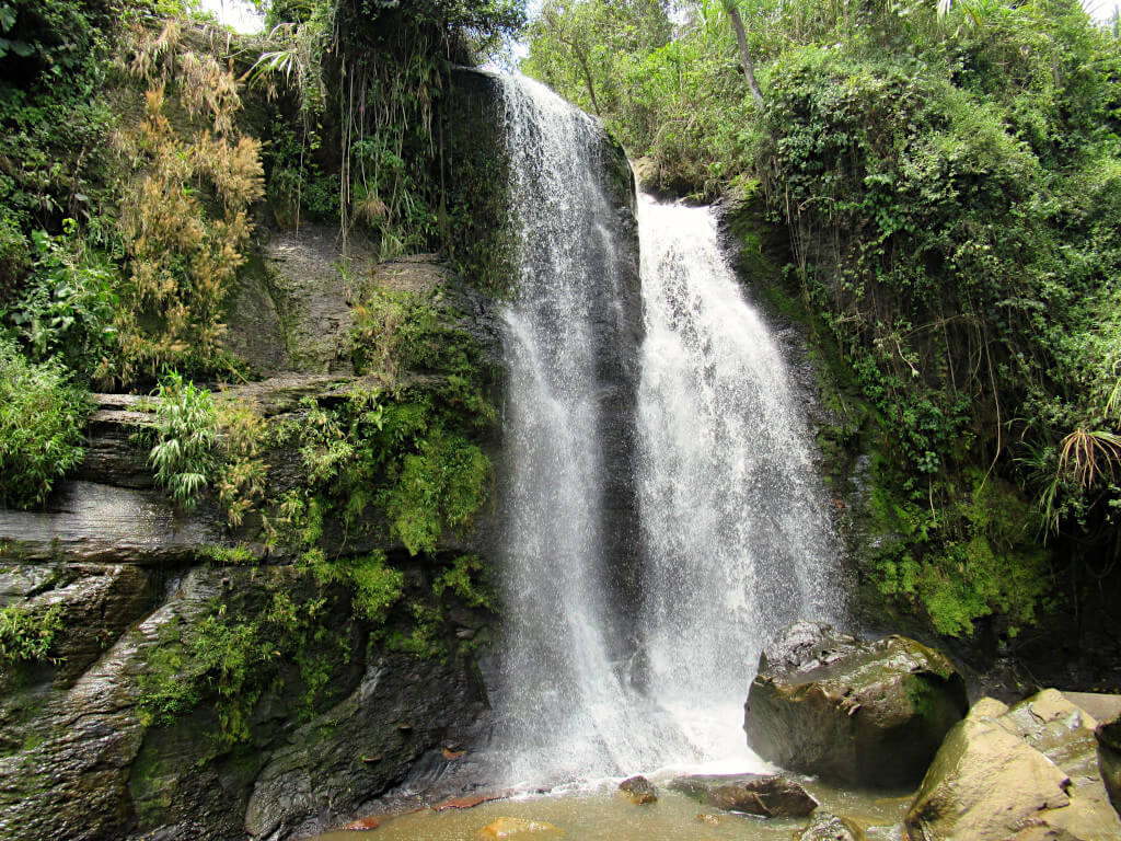 A waterfall at Tres Cascadas. The powerful flow of water crashes in to the plunge pool and onto the rocks below