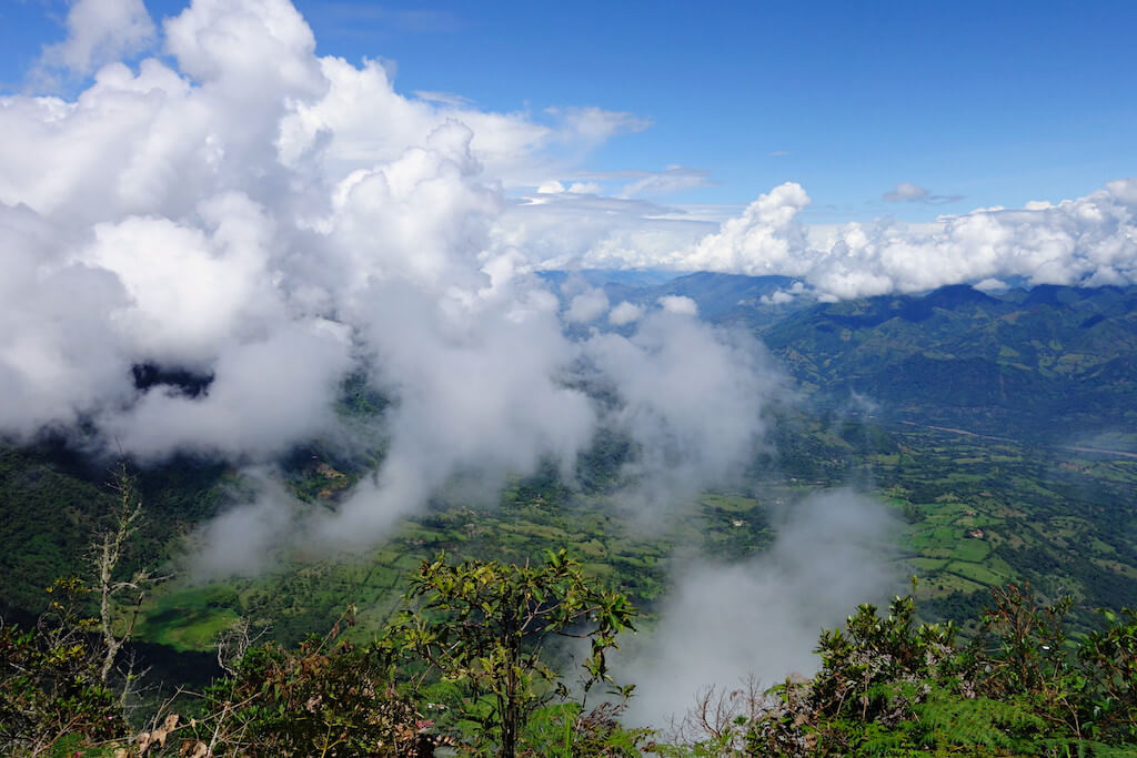 Looking out from Cerro Las Nubes in Jercio, Colombia. Low cloud hangs across the valley with lots of lush green fields visible between them