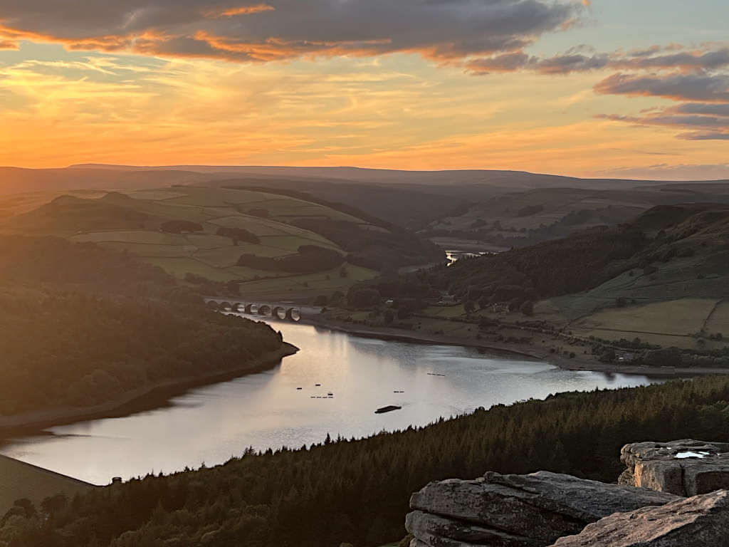 Ladybower Reservoir surrounded by Alport Castles and Derwent Edge with a glowing orange sky