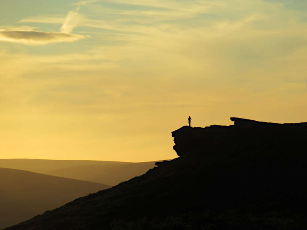 A single silhouette against the yellow-blue sky just before sunset