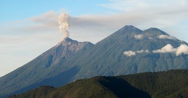 An ash cloud spewing from the crater of Fuego volcano, with Acatenango visible on the right. These are two of the best volcano hikes in Guatemala