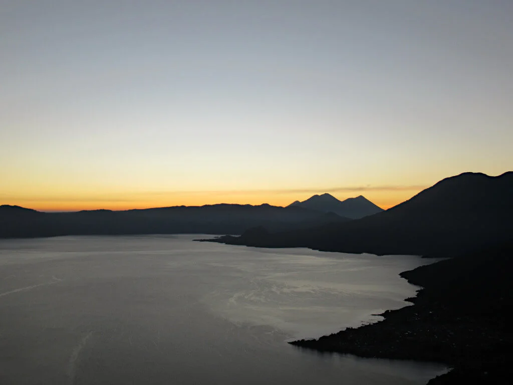 Daybreak over Lake Atitlan, Agua, Acatenango and Fuego volcanos are in the centre of the image, with the still water of Atitlan in the foreground