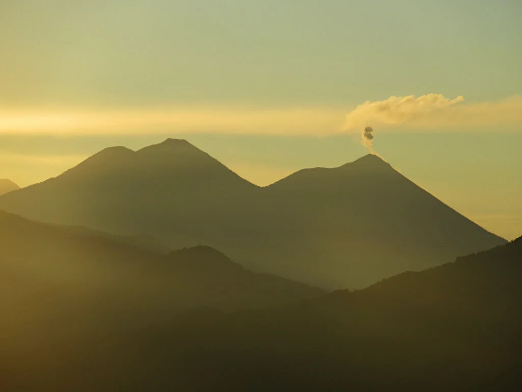 The sun rises as smoke lifts from the top of Fuego Volcano, Acatenango is on the left of the image