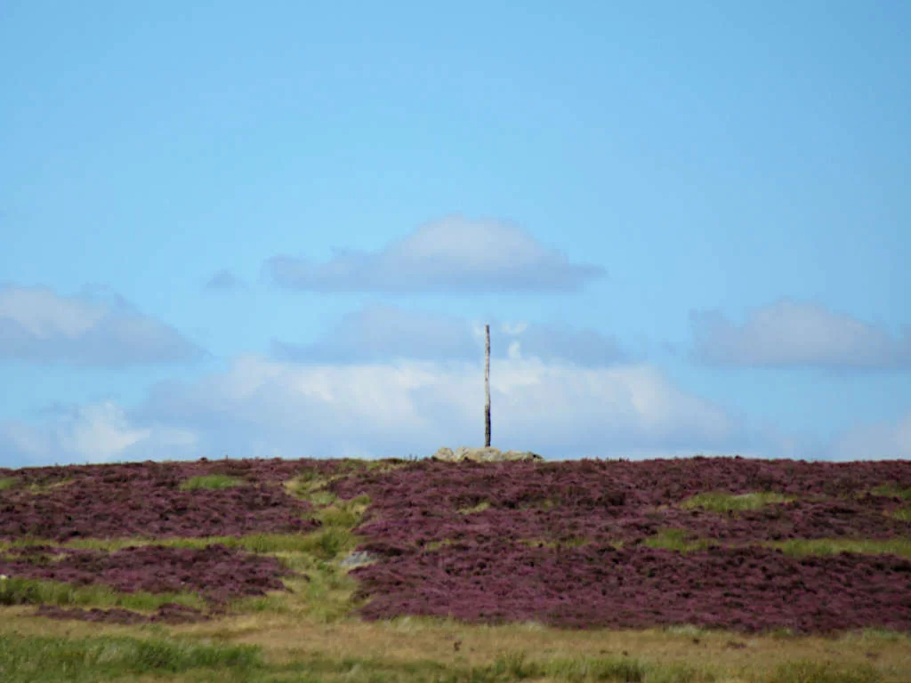 The Stanage Pole marking the boundary between Derbyshire and South Yorkshire against a blue sky backdrop