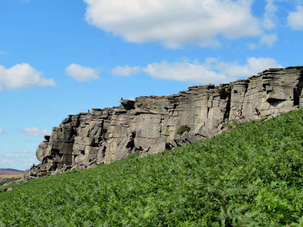 Climbers scattered along the rockface under the backdrop of a bright blue sky