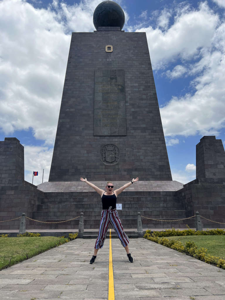 Zoe stood on the Quito equator with the monument behind