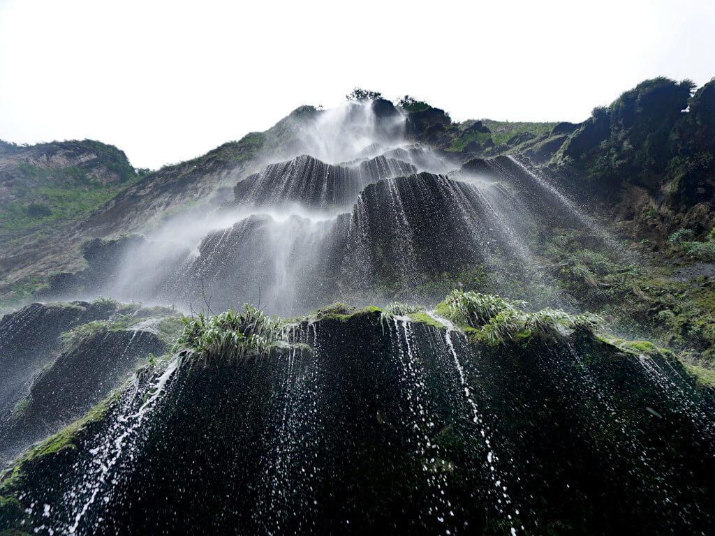 Looking up at a waterfall from directly underneath as the water falls towards the camera