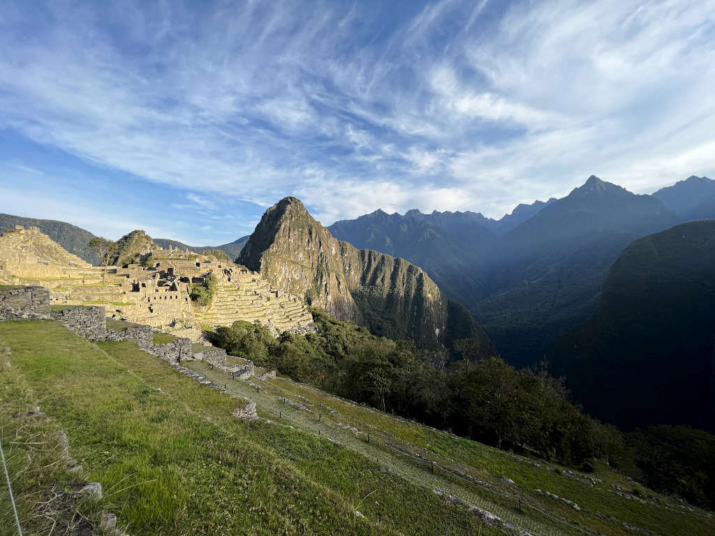 Sunrise over Machu Picchu with a golden glow and wispy clouds
