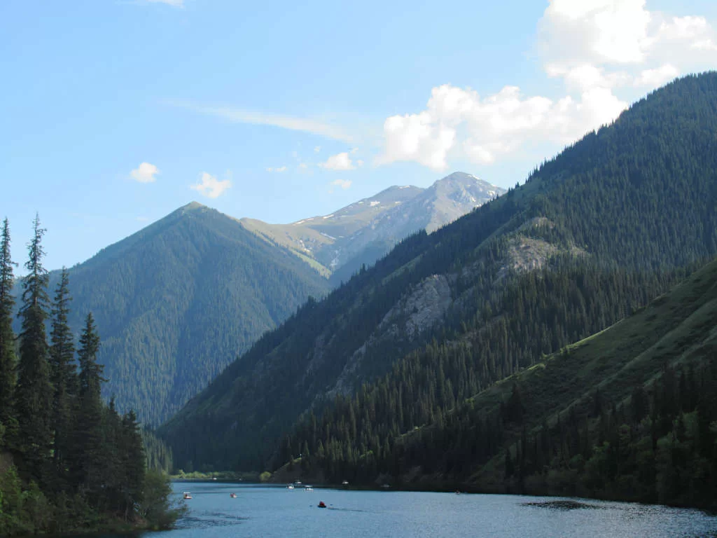 Looking across Kolsay Lake at the peaks of hills and mountains, surrounded by trees