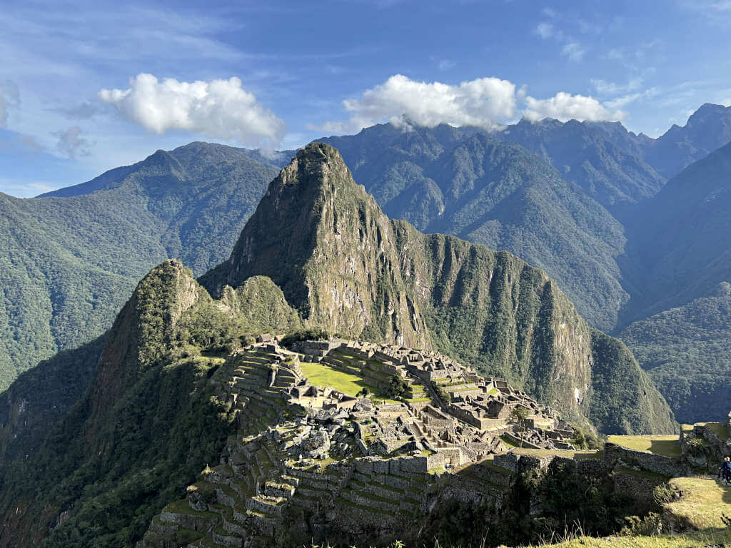 The iconic, postcard-perfect view of Machu Picchu with Huayna Picchu behing and tree-covered mountains all around