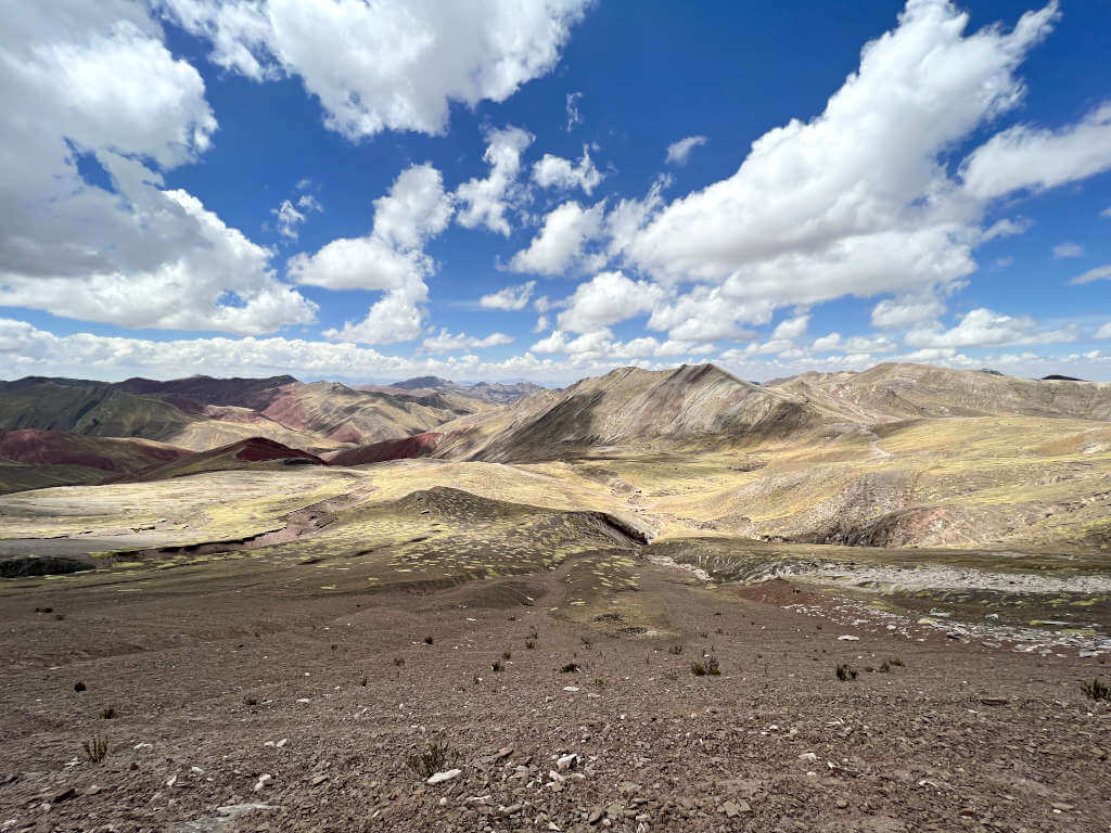 The vast valley around Palcoyo Mountain, with deep reds, fields of green and rainbow-coloured mountains