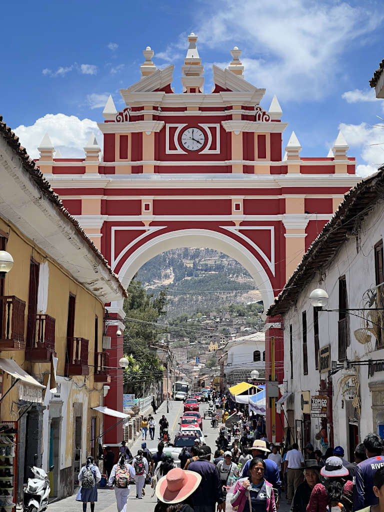 The main pedestrian street in Ayacucho with a large arch that's red and beige coloured.