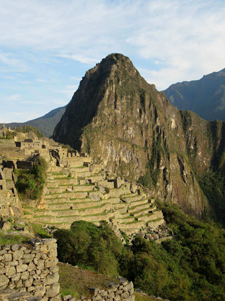 Early mornings in Machu Picchu with a golden hour glow over Huayna Picchu and the stone ruins