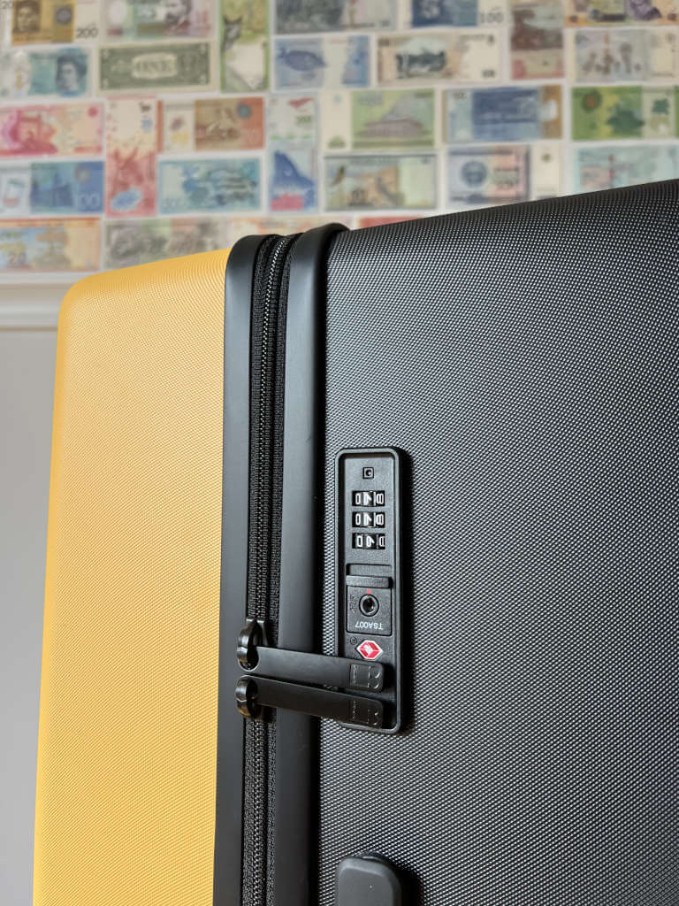 A close-up shot of the TSA-approved combination lock on the yellow LEVEL8 suitcase