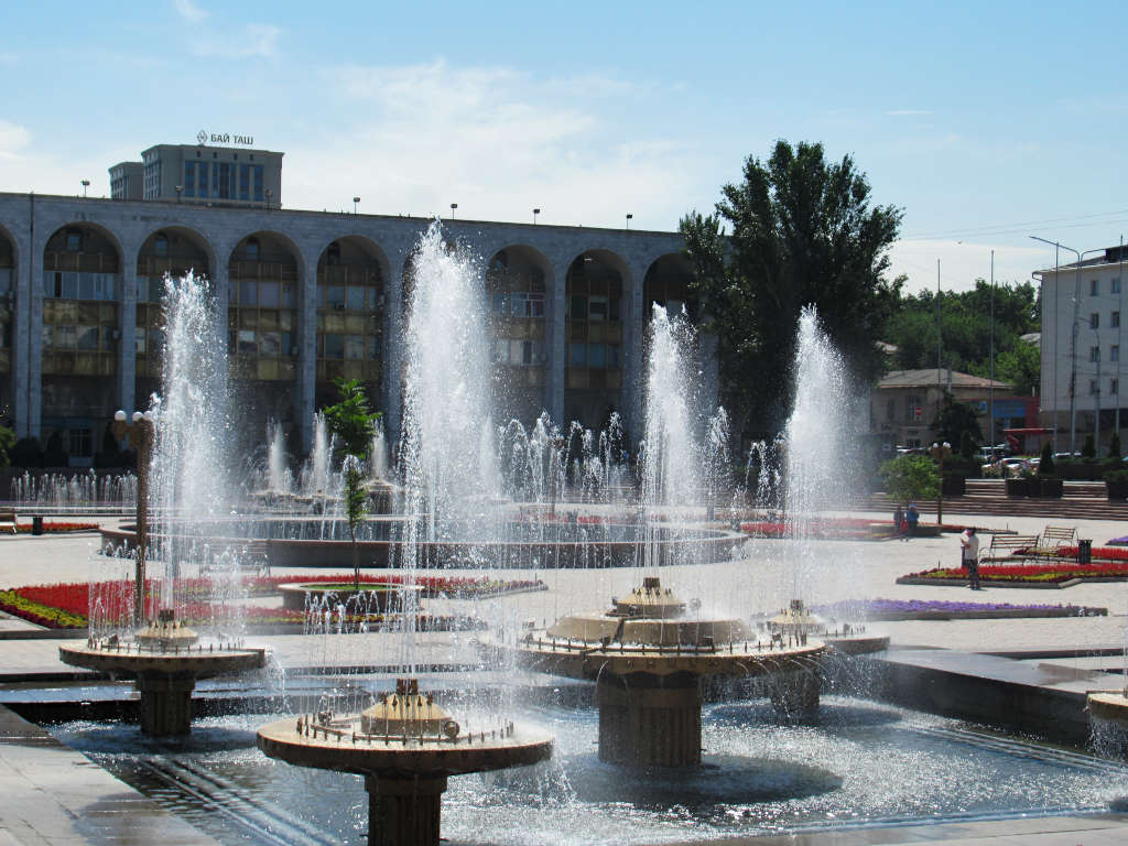 The fountains of Ala-Too Square Bishkek. Flowerbeds and buildings surround the spray of water coming from each water jet