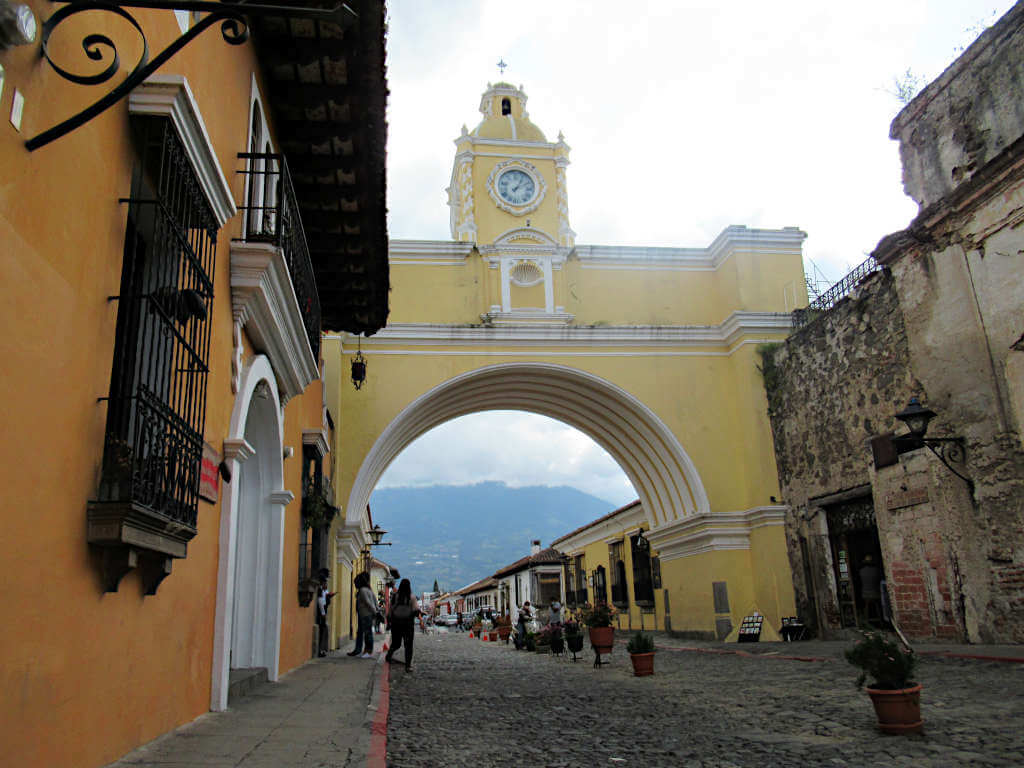 The famous arch in Antigua Guatemala. Agua volcano is partially visible through the arch but clouds obscure most of it.