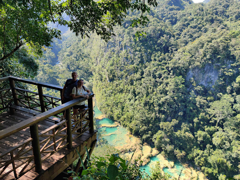 Zoe and Adam stood on the viewpoint edge with the pools and jungle of Semuc Champey behind