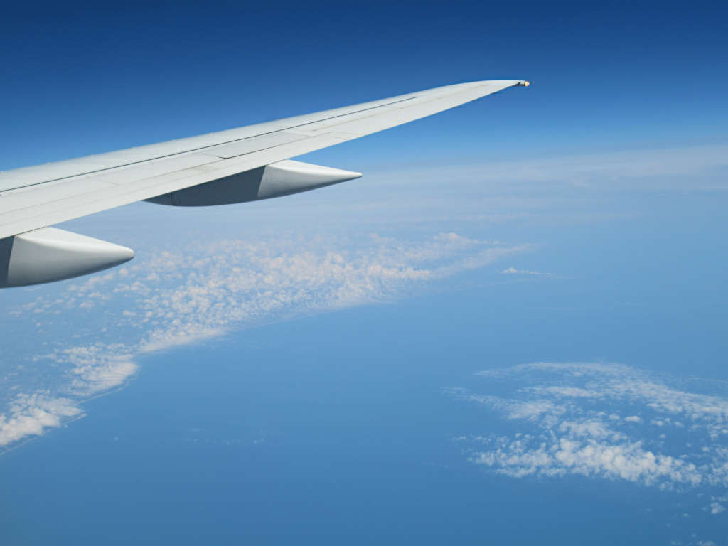 Looking out the window of the Jet2 plane over the sea and clouds, the wing is visible on one side of the photo