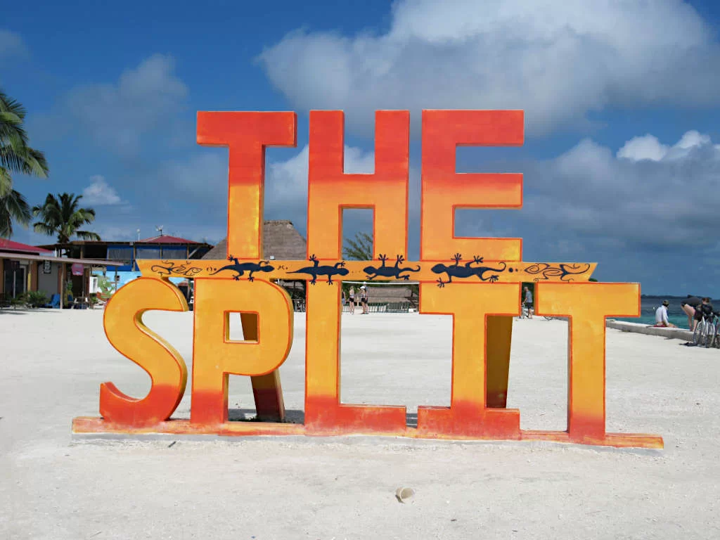 A sign that has the words 'The Split' in red and yellow, located near The Split in Caye Caulker