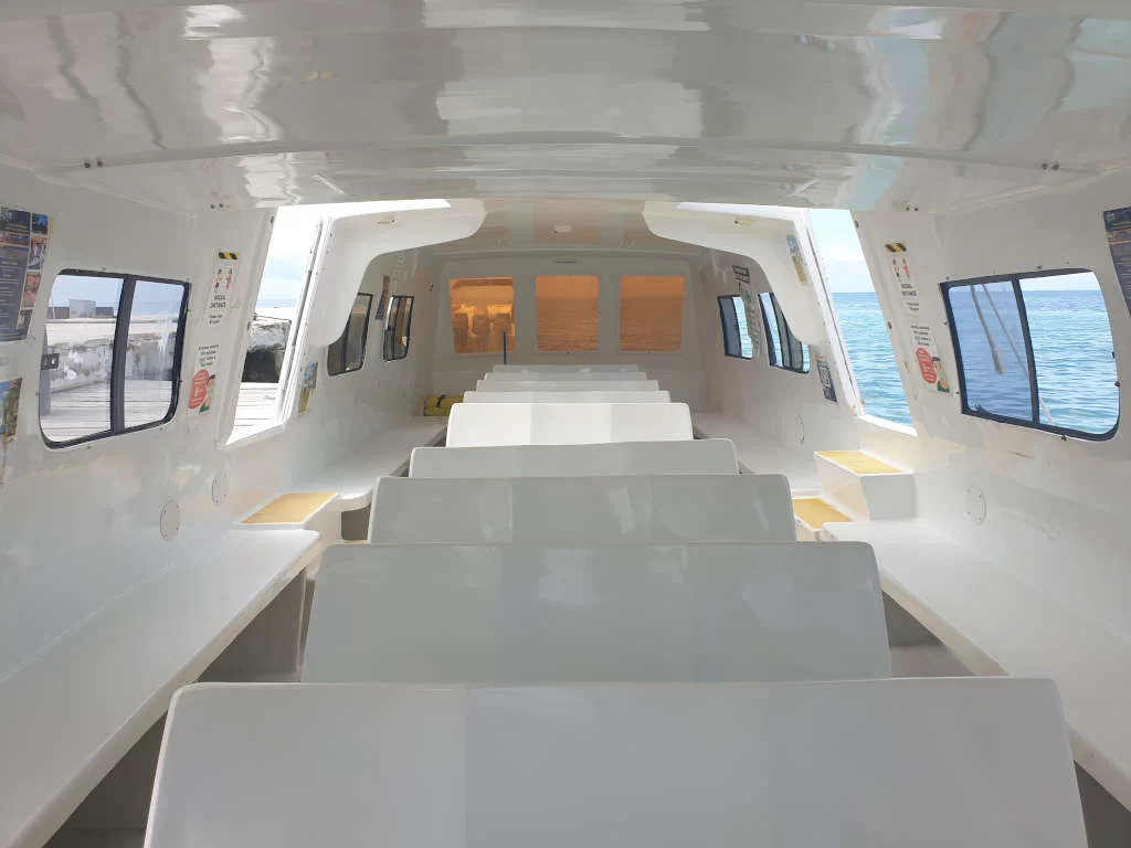 Inside of a boat with lots of seats that are white benches