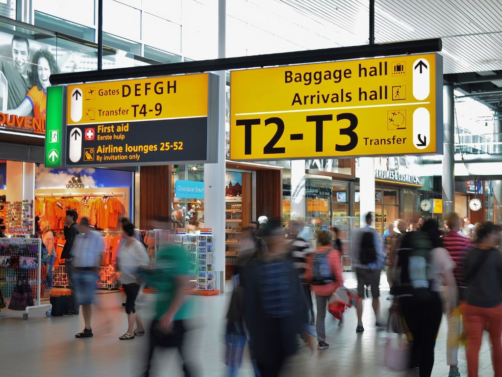 Inside an airport, sign is pointing towards the terminals and baggage hall