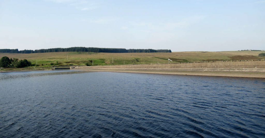 The long reservoir wall with dark blue water in the foreground