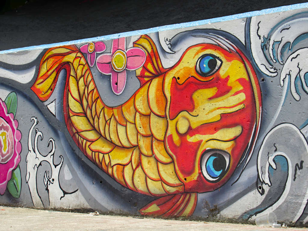A painting of a gold and red fish on a wall.
