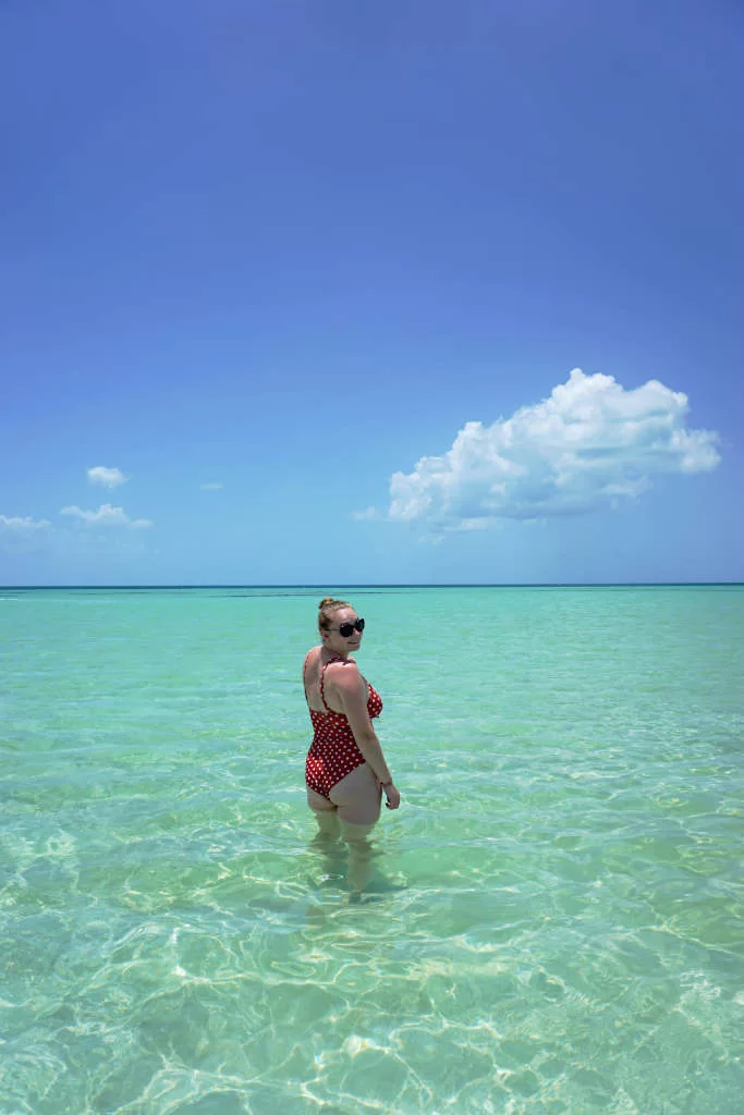 Zoe stood with her back to the camera looking over her right shoulder thigh-deep in the clear sea.