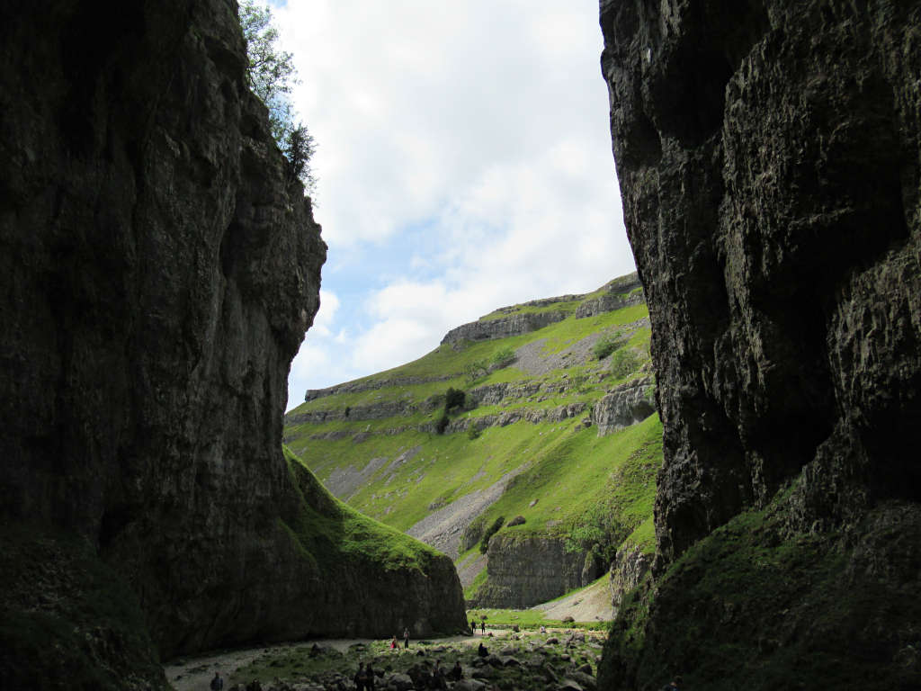 Inside Gordale Scar just outside of Malham. The bright green hillside is visible through the narrow gorge opening