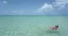 Zoe floating in the sea off the coast of Holbox at Punta Mosquito. The water is calm and clear. She is wearing a red-brown swim suit