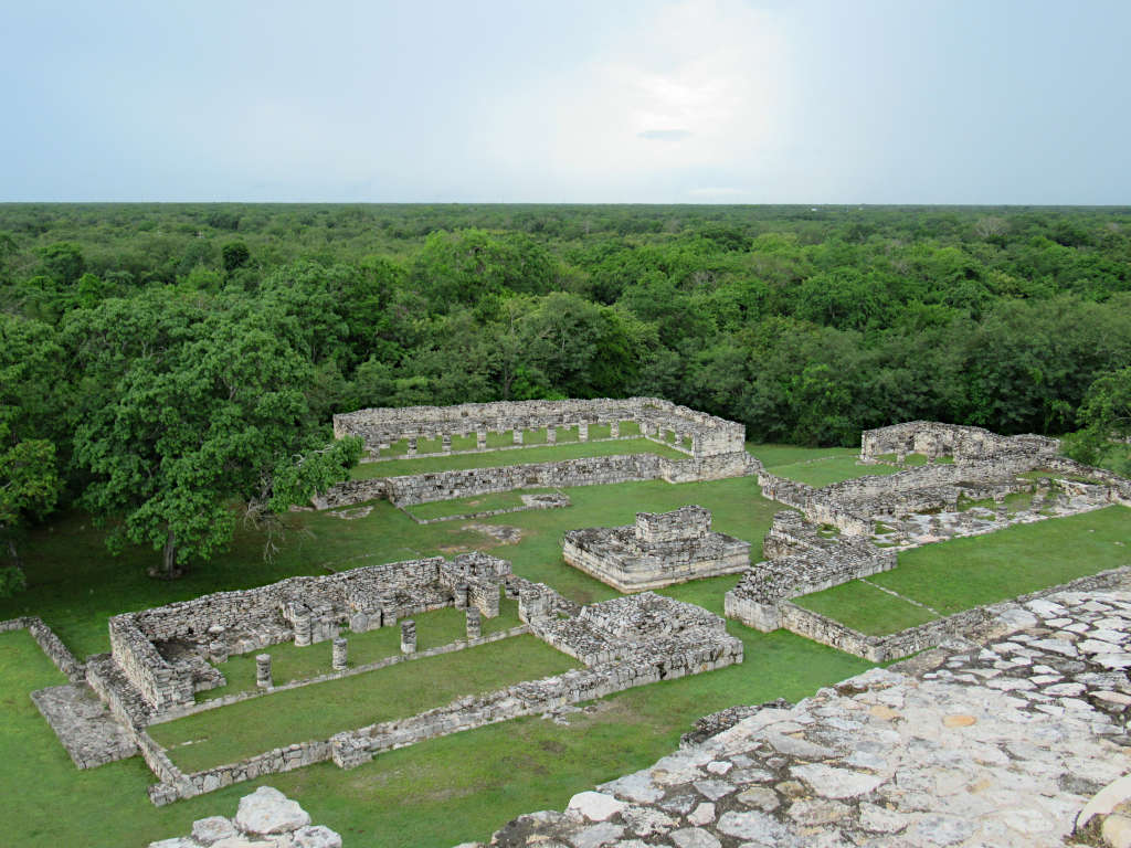 Looking down on the Mayapan Archaelogical Site in Mexico from the top of the main pyramid - thick forest surrounds the edges of the ruins